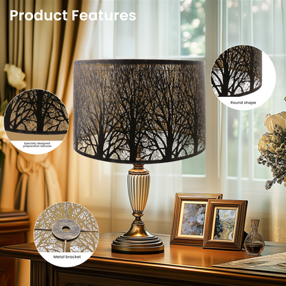 Decorative table lamp with tree design shade on a wooden table.