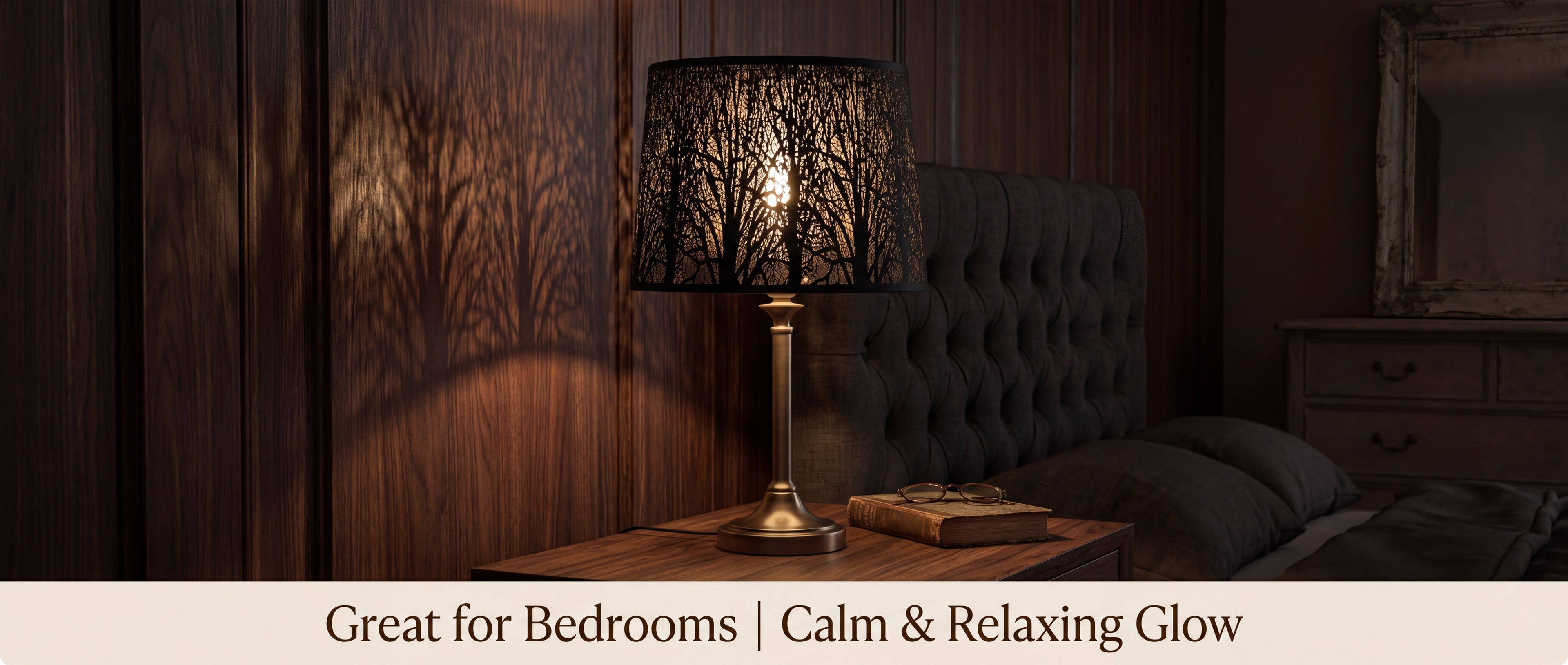 Large black metal replacement lamp shade with spider fitter on a bedroom table lamp, producing a calm warm glow and soft tree shadows.