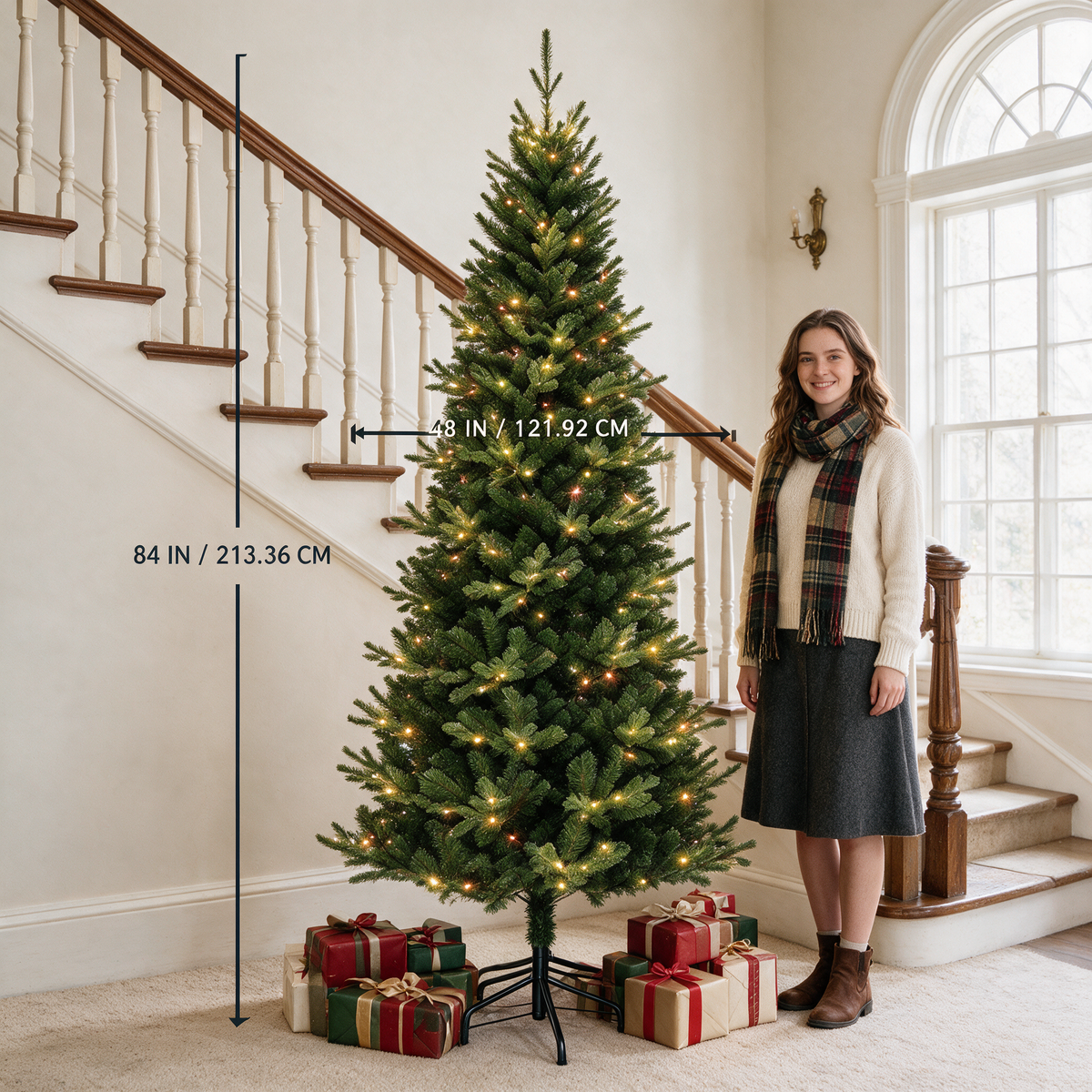 7 ft green artificial Christmas tree with warm lights beside a woman, labeled 84 inches tall and 48 inches wide.