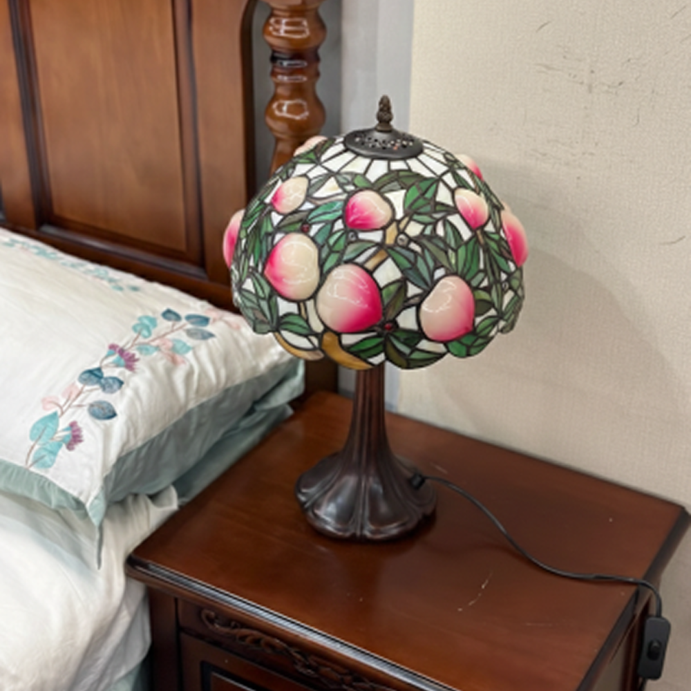 Ornate antique bronze lamp base with vintage detailing supporting peach fruit stained glass Tiffany shade