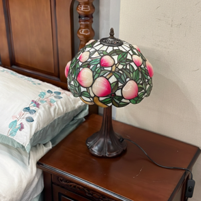 Ornate antique bronze lamp base with vintage detailing supporting peach fruit stained glass Tiffany shade