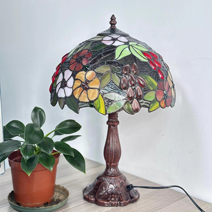 Ornate antique bronze lamp base with vintage detailing supporting colorful floral stained glass Tiffany shade