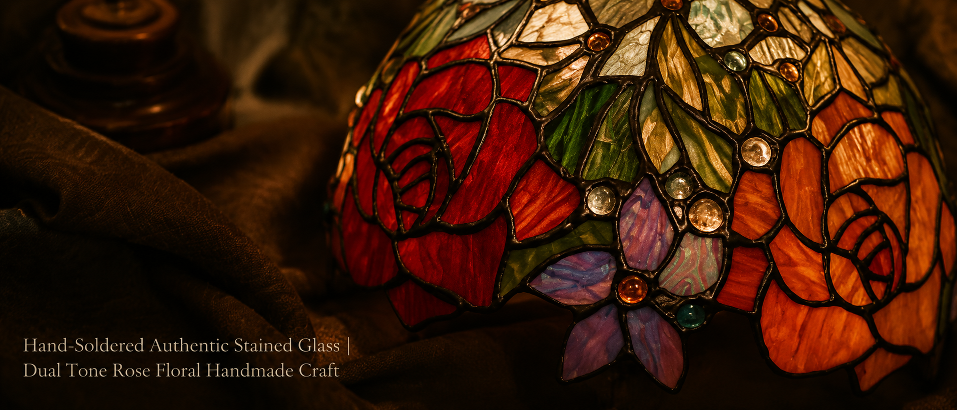 Detailed view of hand-soldered stained glass with red and amber roses, green leaves and decorative jewel accents