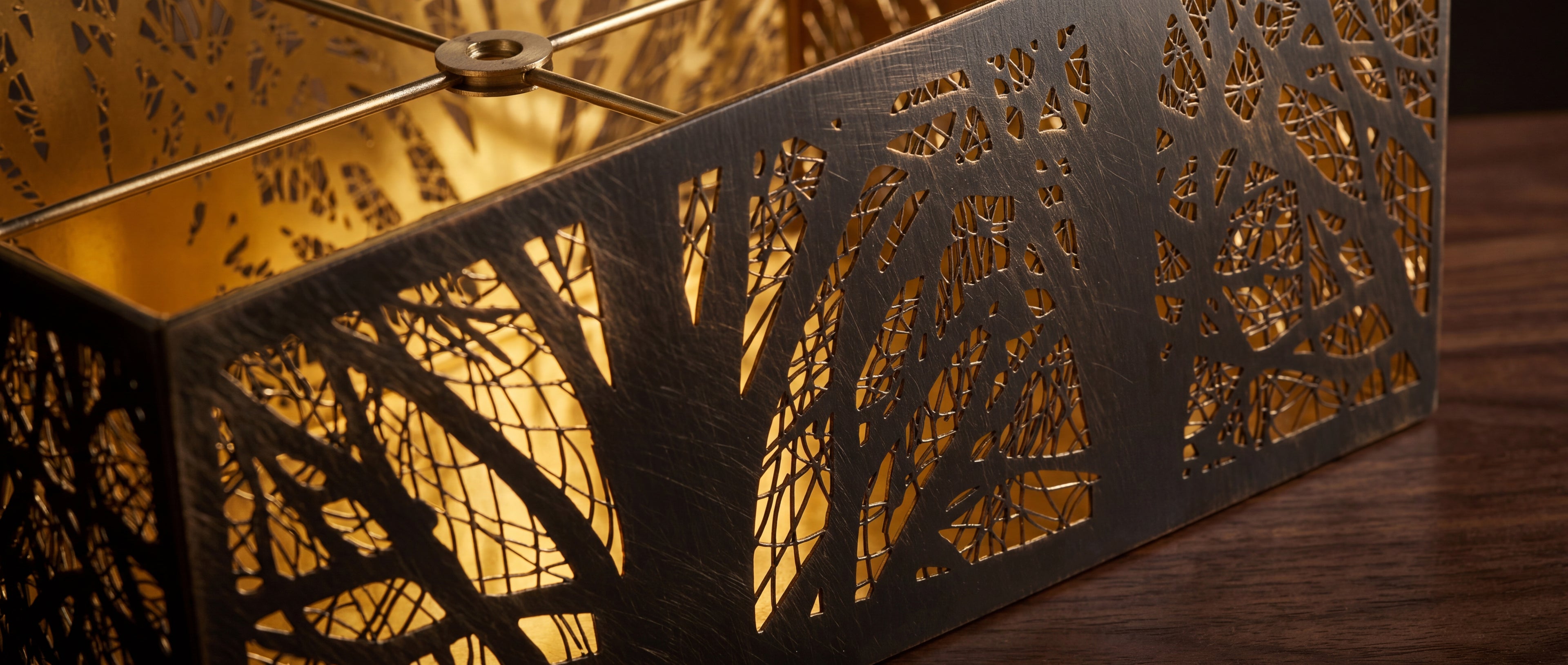 Etched botanical tree pattern metal lamp shade closeup detail, dual-tone bronze exterior with gold interior, precision laser cut metal construction vintage industrial finish