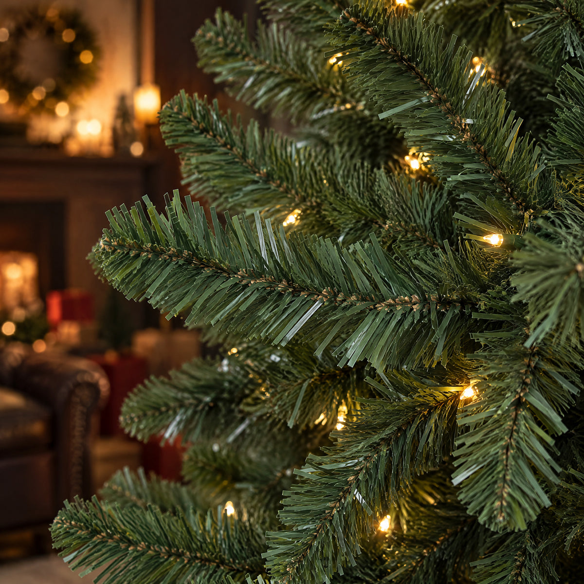 Close-up of green artificial Christmas tree branches with warm white LED lights, highlighting the layered evergreen needles and soft festive glow.