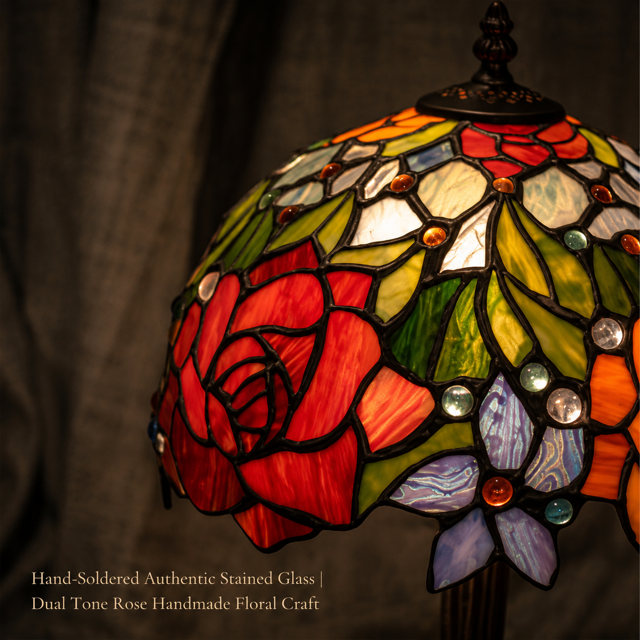 Close-up of hand-soldered stained glass featuring red rose, golden floral, green leaf and jewel-like glass details