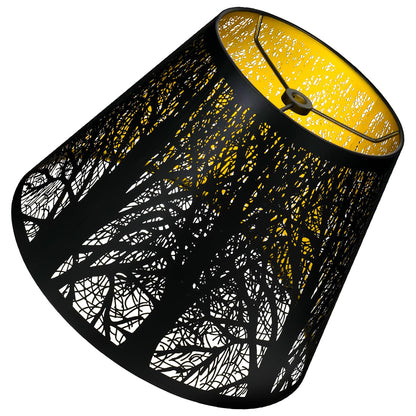 A small metal lampshade with a hand-etched forest design, featuring a black exterior and gold interior.