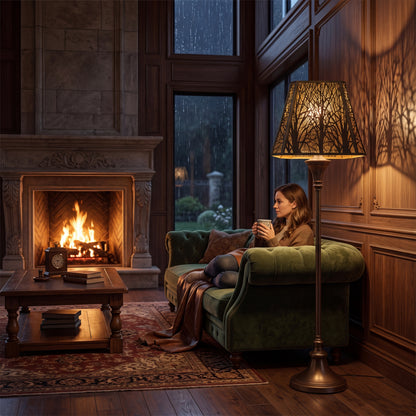 Large forest metal lamp shade on a floor lamp in a cozy reading room with a fireplace and warm ambient lighting.