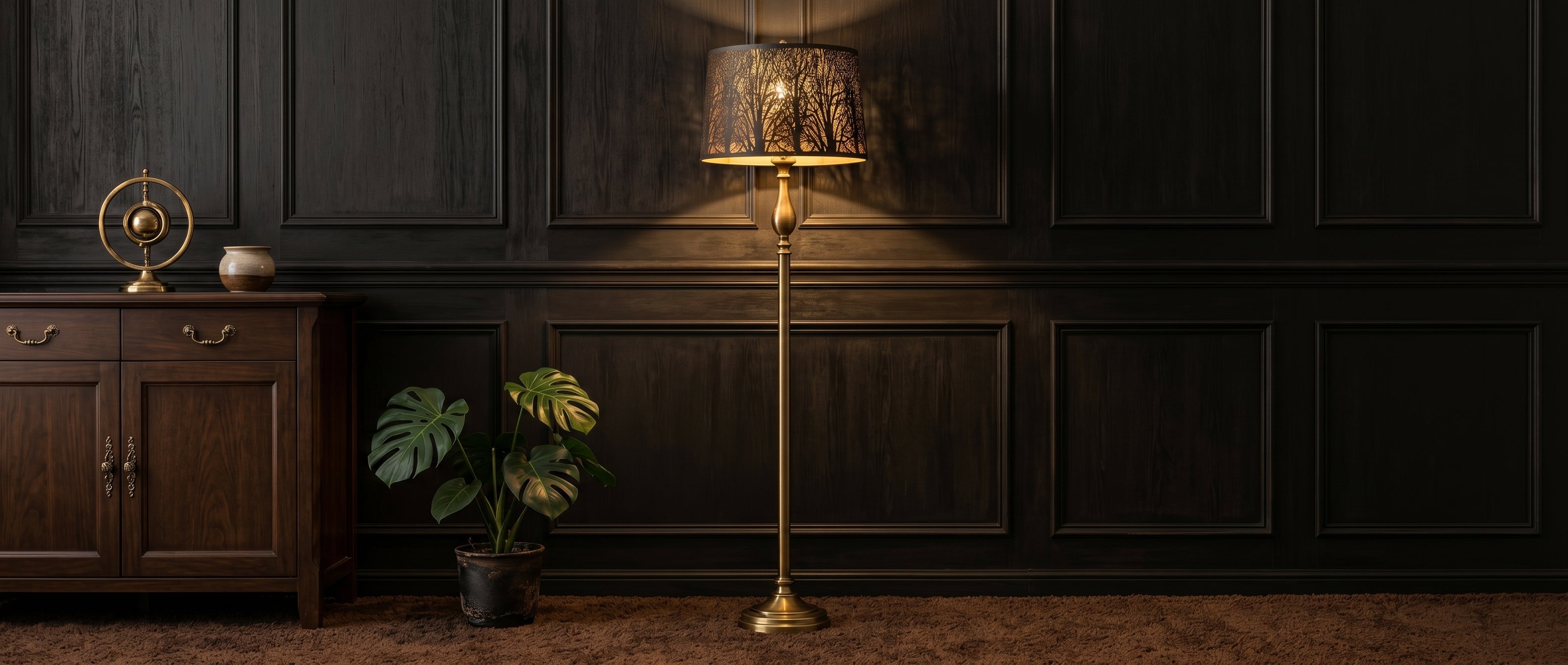 Large Forest Etched Metal Lamp Shade on Slender Brass Floor Lamp with Elegant Urn-Shaped Stem and Decorative Flared Base in Sophisticated Dark Wood Paneled Living Room or Study with Rich Black or Espresso Panel Moldings, Walnut Wood Console Table or Sideboard with Decorative Brass Handles, Brass Armillary Sphere (Armillary or Astrolabe), Two-Tone Ceramic Vase, Lush Green Monstera Deliciosa Houseplant in Dark Pot, Plush Chocolate Brown Shag Carpet or Area Rug - Antique Bronze or Matte Black Metal Drum Shade 