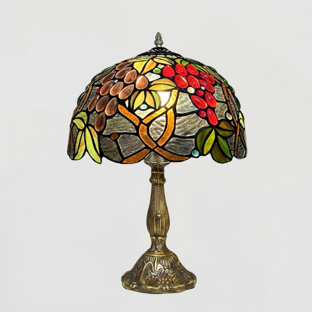 Vintage fruit stained glass table lamp emitting warm glowing orchard light in dark cozy cottagecore atmosphere