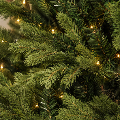 Close-up of green artificial Christmas tree branches with realistic layered evergreen tips and glowing warm white LED lights.