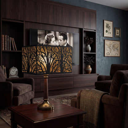 Rectangular Metal Lamp Shade with Laser-Cut Tree Pattern on Wood and Brass Table Lamp in Modern Dark Wood Home Theater Living Room - Brown Leather Sofa, Plaid Throw Blanket, Built-in Dark Walnut Media Cabinet with Flat-Screen TV Playing Classic Black-and-White Movie, Leather Books on Shelf, Brass Vintage Clock, Ceramic Vases with Dried Branches, Botanical Prints and Antique World Map Framed Art on Dark Blue-Green Textured Wall, Vintage Oriental Rug - Black Metal Exterior with Intricate Laser-Cut Bare Winter