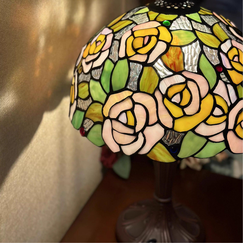 Tiffany style table lamp casting a warm romantic glow through pink rose stained glass for bedroom ambiance