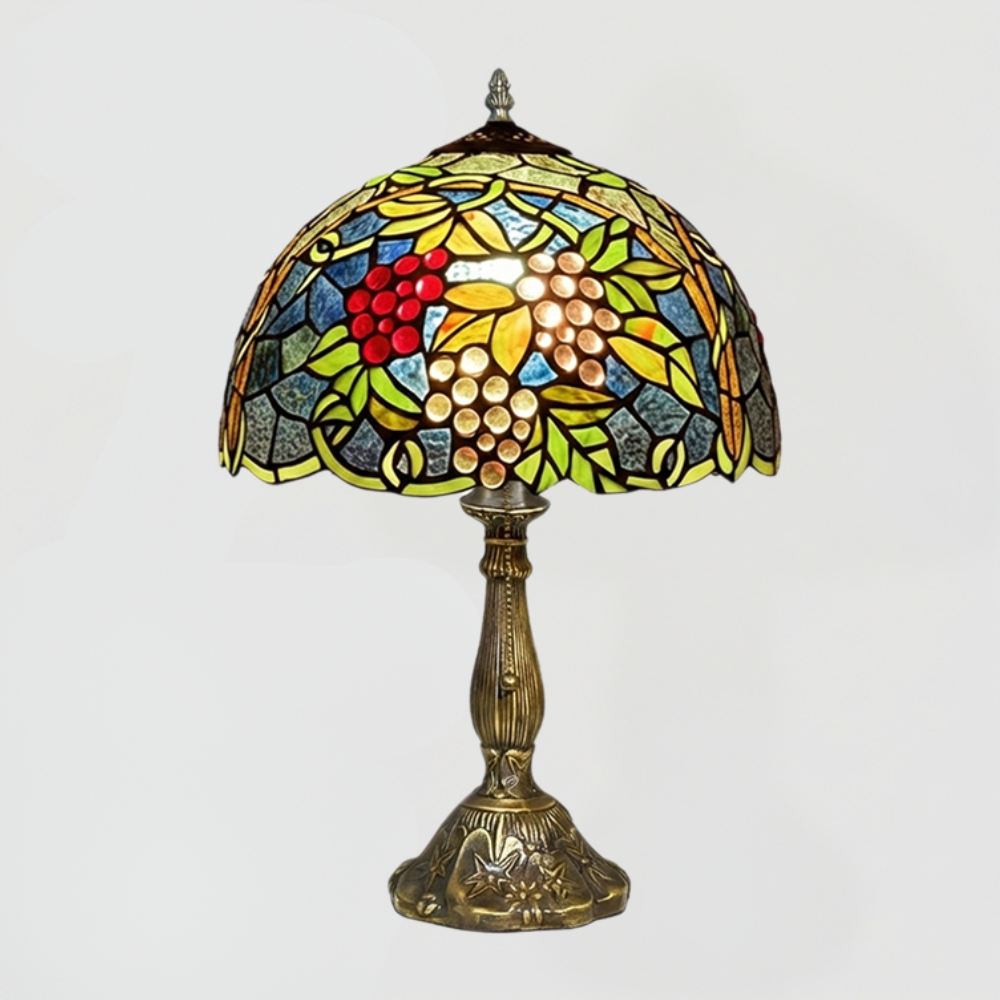 Vintage grape cluster stained glass table lamp emitting warm amber glow in cozy rustic vineyard inspired night setting