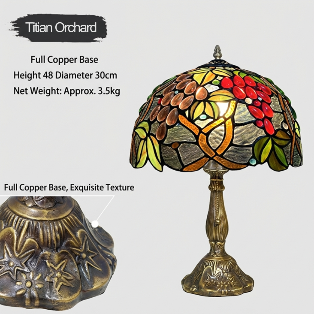 Close-up of handcrafted Tiffany stained glass shade with vintage fruit orchard design in amber crimson and green glass tones