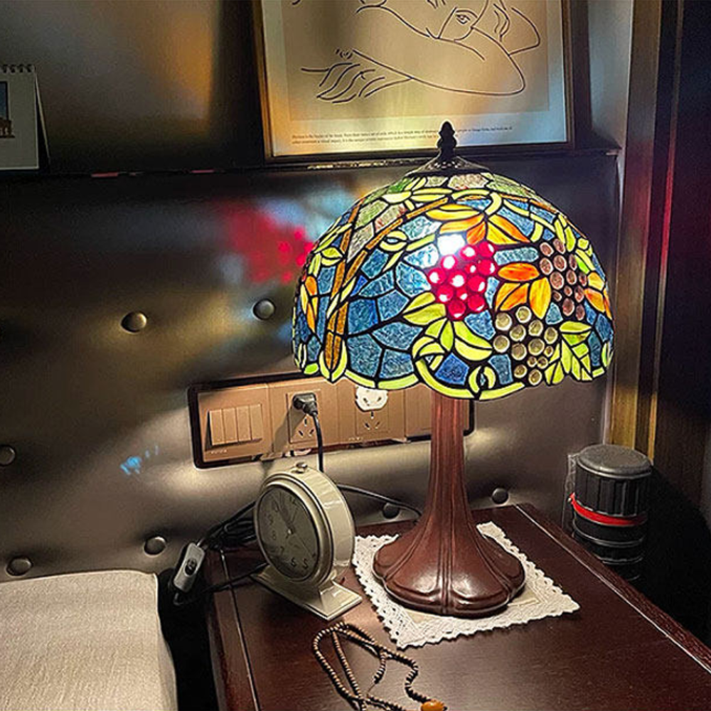Close-up of handcrafted Tiffany stained glass shade with grape cluster design in rich purple and amber tones inspired by vineyard vines